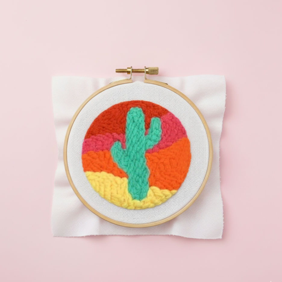 Embroidery hoop with colorful cactus design on a pink background